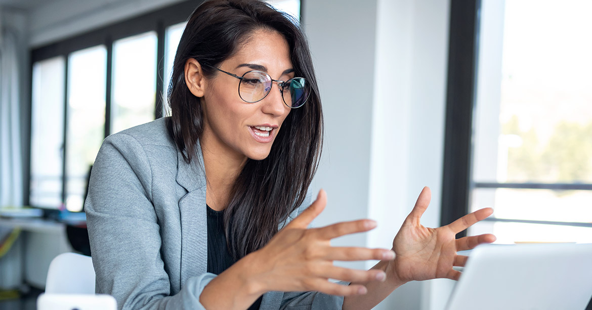 Woman in grey blazer expressively talks on video call