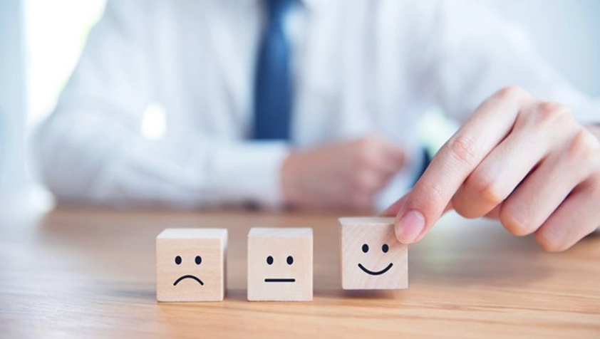 Man in shirt and tie holds wooden block with smiley face