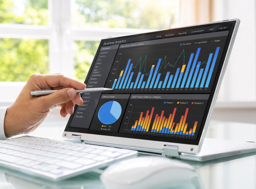 Hand points to data and charts on a laptop screen