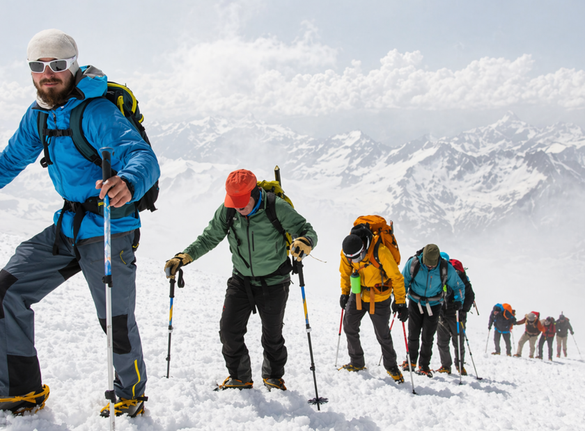 Group of mountain climbers climb snowy mountain in ski gear.