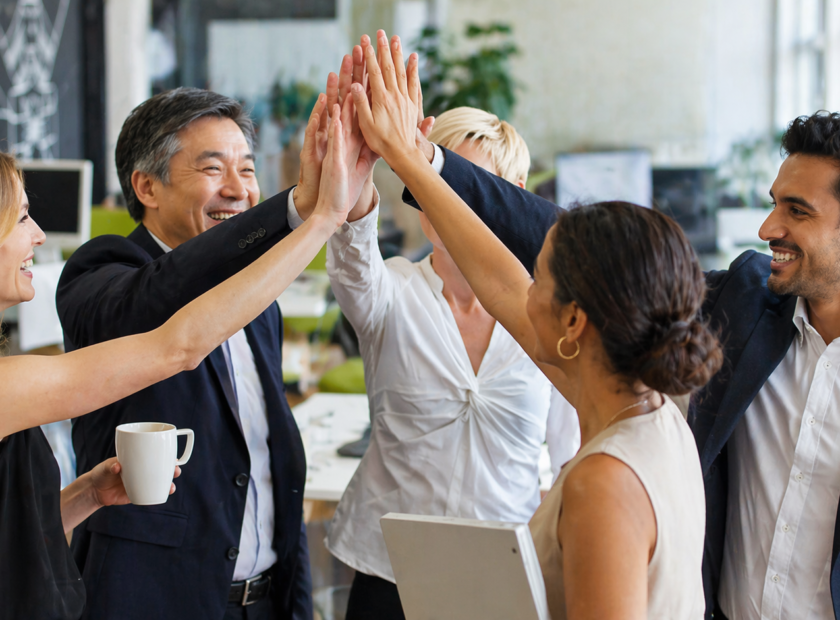 Group of colleagues high 5 with big smiles in their office.