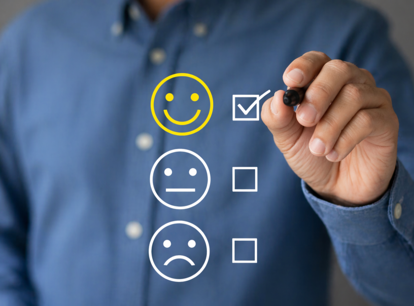 Man in a blue button-up shirt checks a yellow smiley box floating in air.