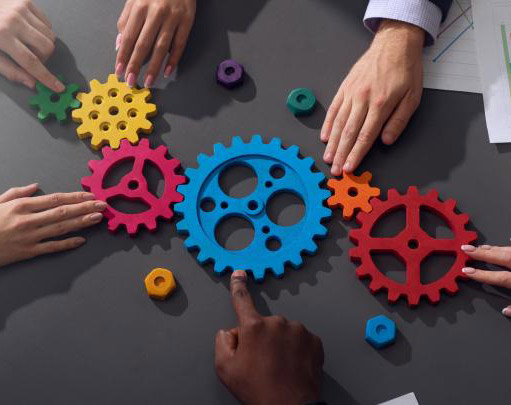 Business people's hands work together connecting colorful gears, demonstrating teamwork.