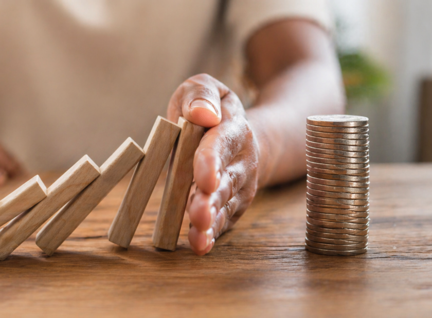 Woman prevents wooden blocks from falling into a stack of coins.