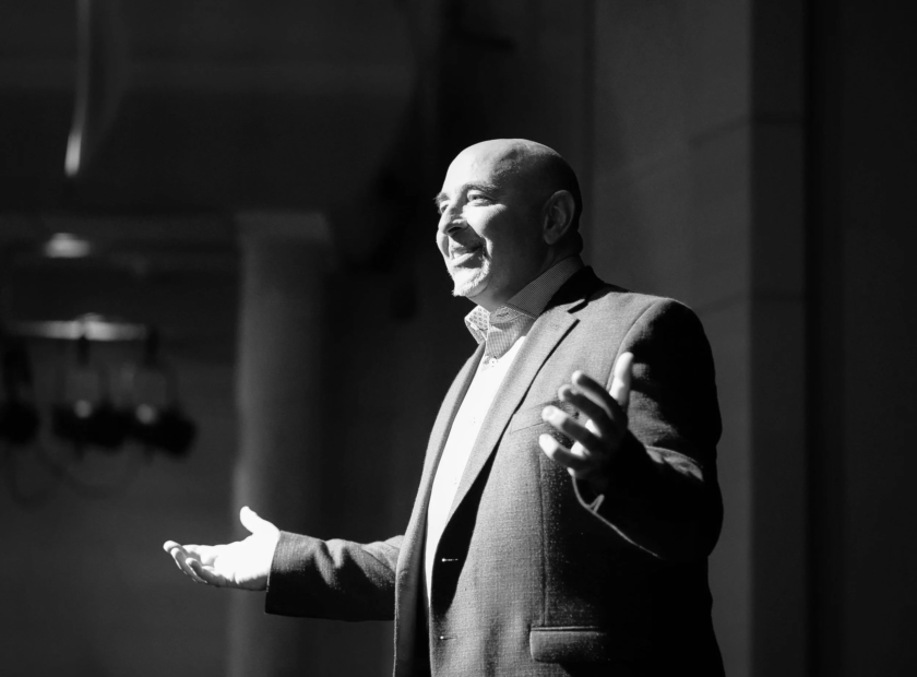 Black and white photo of Gair Maxwell speaking to an audience.